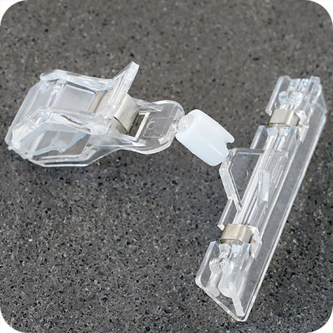 legatoria Doppia molletta GRANDE-PortacartellinoGRANDE altezza 110mm TRASPARENTE in policarbonato. Composta da 2 mollette, 1 GRANDE (58x25mm) e 1 PORTACARTELLINO (80x15mm) collegate da  giunto a sfera. Altezza totale 110mm.