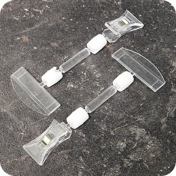 legatoria Doppia molletta Piccola-Portacartellino altezza 130mm TRASPARENTE in policarbonato. Composta da 2 mollette, 1 PICCOLA (38x21mm) e 1 PORTACARTELLINO (50x15mm) collegate da DOPPIO giunto a sfera e gambetto da 38mm. Altezza totale 130mm.