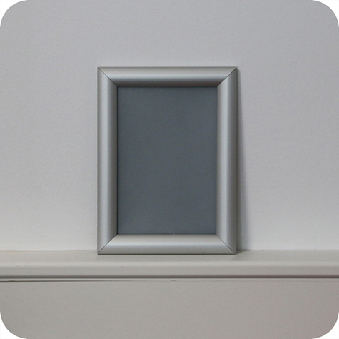 legatoria Cornice alluminio a scatto, A5 AUTOADESIVA mediante nastro biadesivo in schiuma di PE, largo: 19mm, spessore: 1mm. Per fogli di dimensione A5(148x210mm). Dimensioni esterne: 180x240mm. Area visibile: 130x190mm. Profilo: 25mm. La cornice � dotata di foglio protettivo in PVC trasparente antiriflesso..