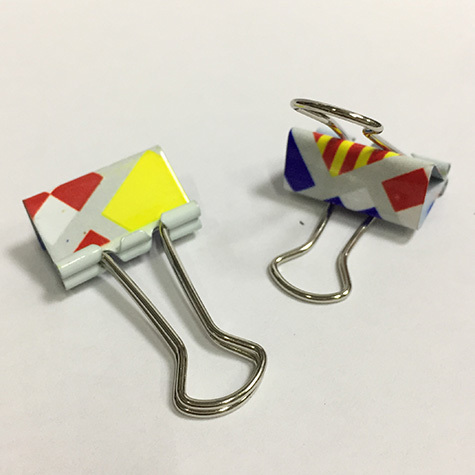 gbc Molle fermacarte doubleclip, 25mm SailingFlags in acciaio, binder clip, con archetti mobili, raccolte in un barattolo di latta con coperchio trasparente la stessa fantasia della mollette, dimensioni barattolo: diamtero 65mm, altezza 75mm. Linea Funny desk by Molho Leone.